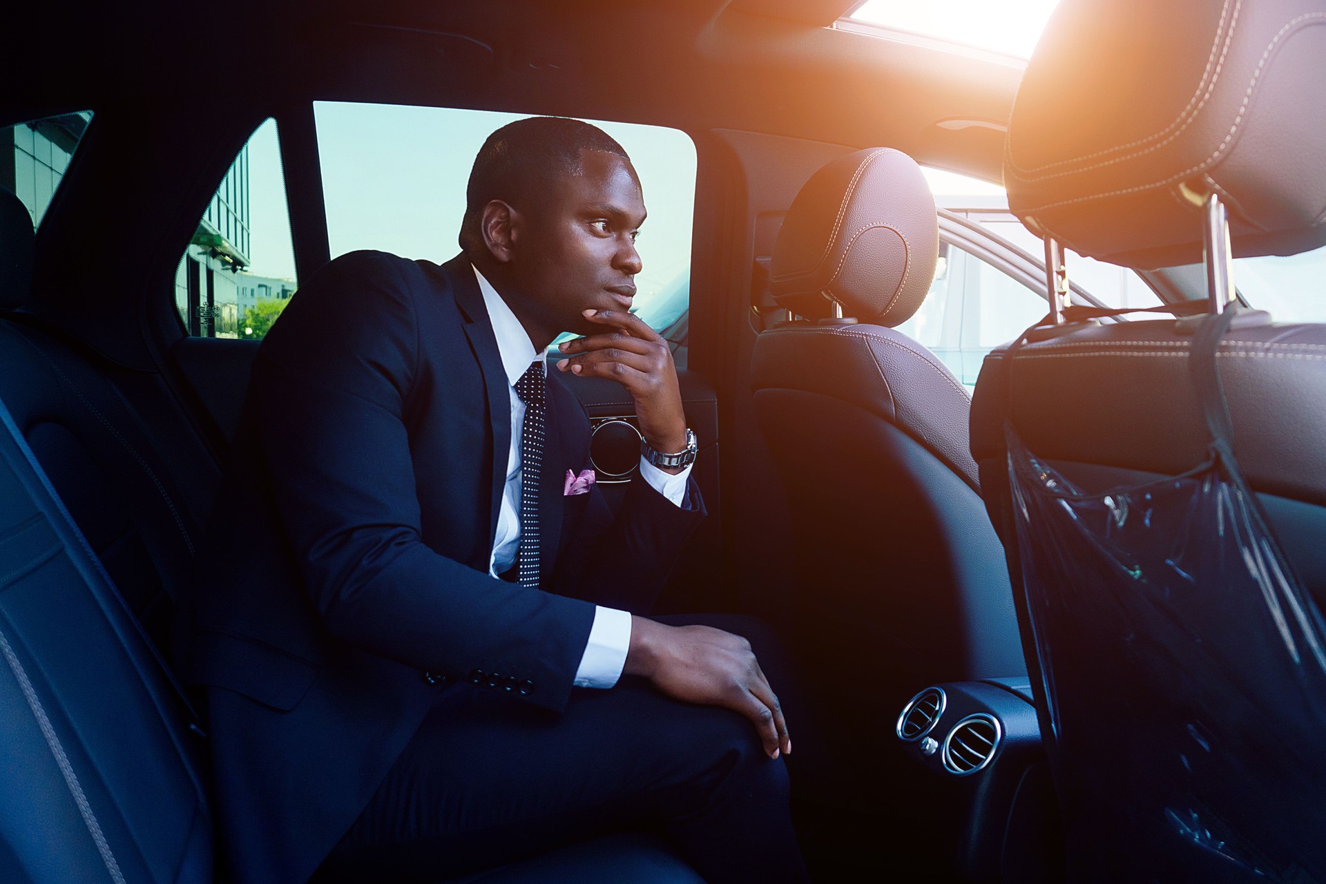 Handsome successful rich african american businessmen in a stylish black business suit and tie sitting in a luxury car. concept of luck and career growth